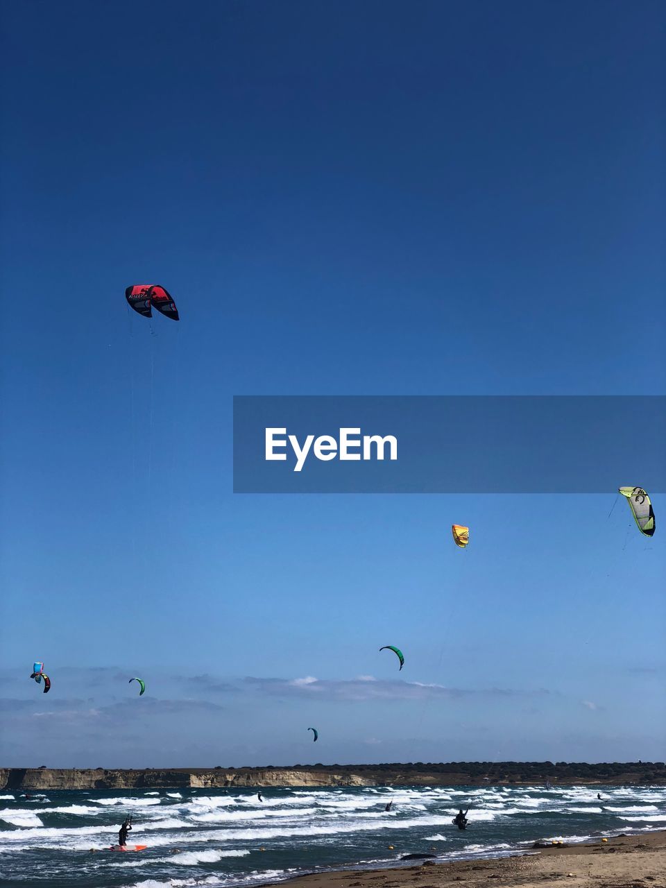 KITE FLYING OVER SEA AGAINST CLEAR SKY