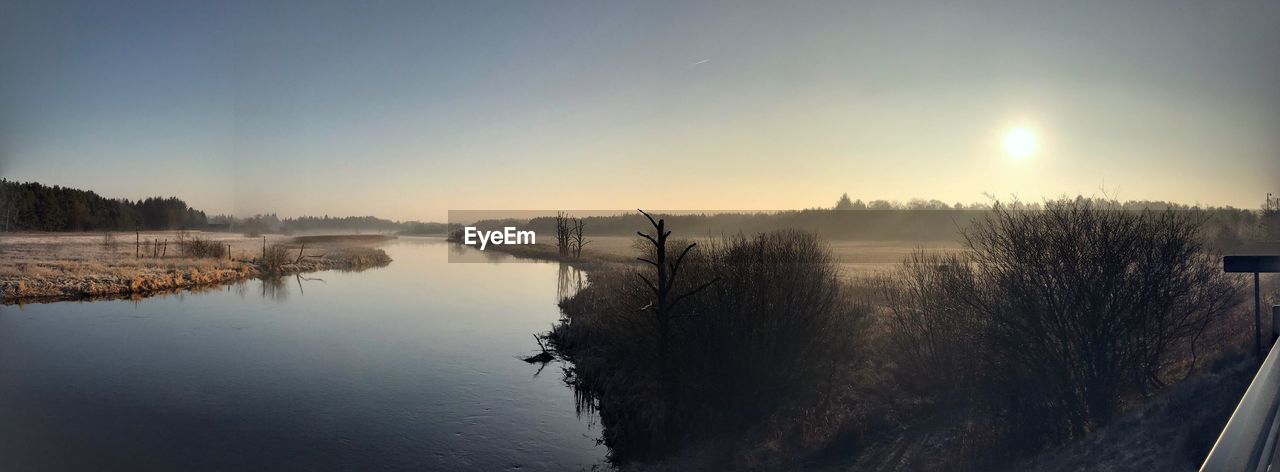 SCENIC VIEW OF LAKE AGAINST SKY AT SUNSET