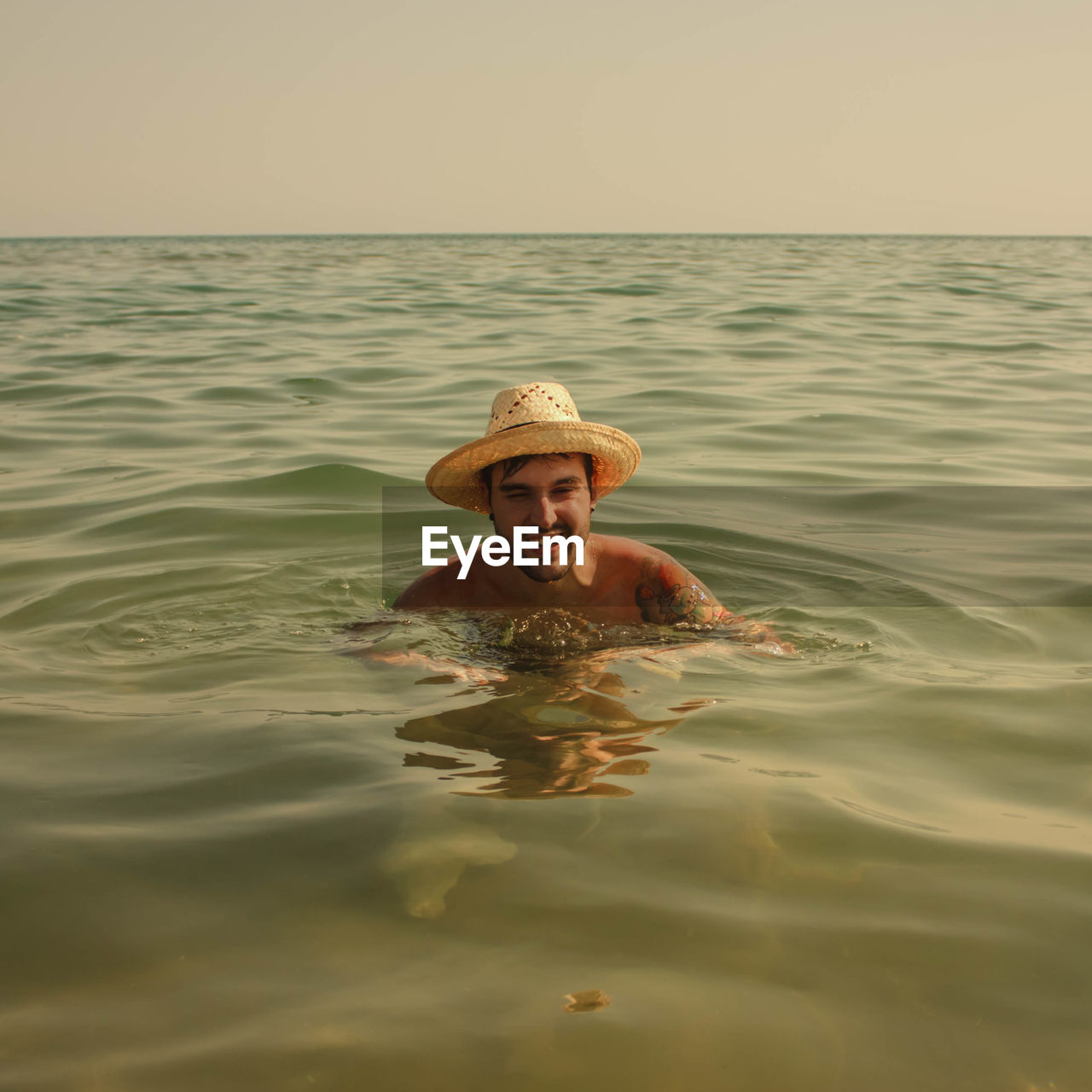 Portrait of happy man swimming in sea during sunset