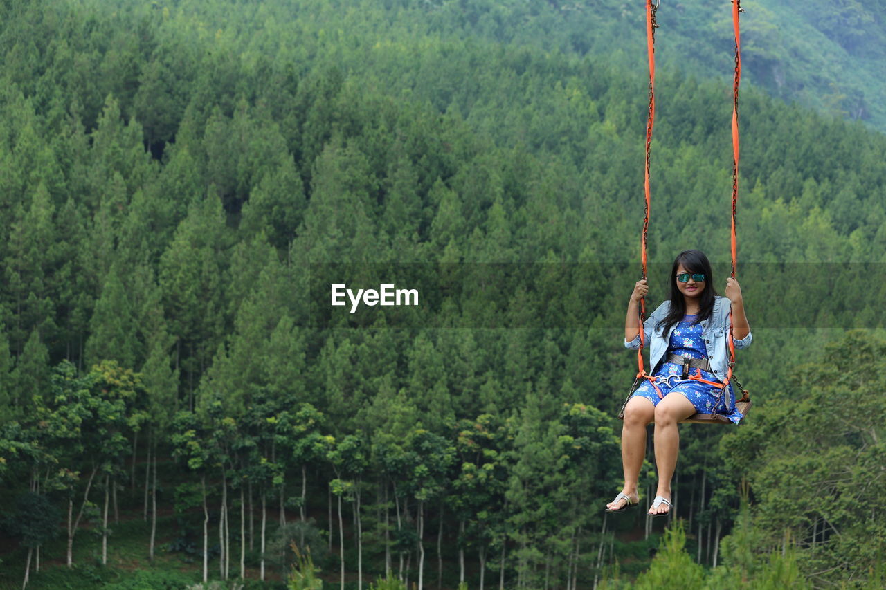 Full length of young woman sitting on swing