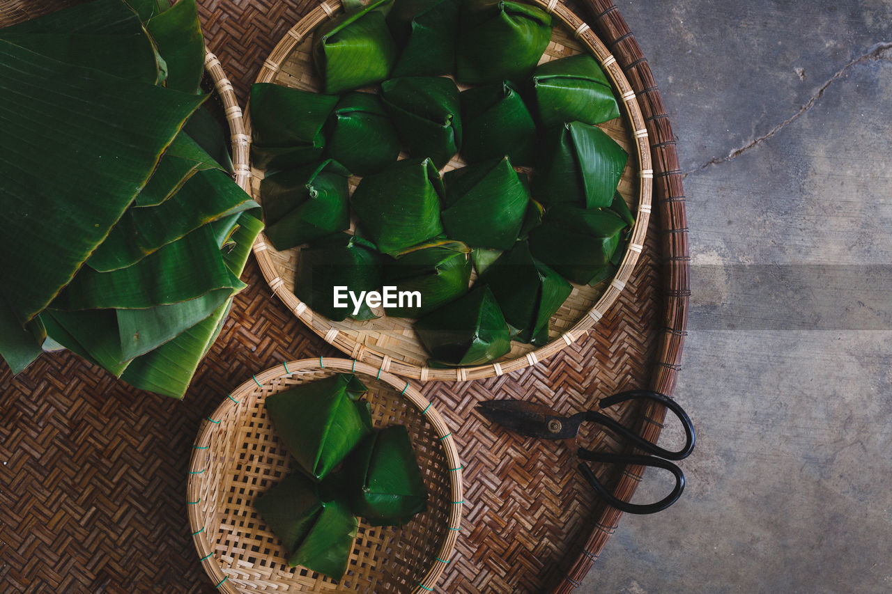 Directly above view of rice cakes wrapped in banana leaves on bamboo tray