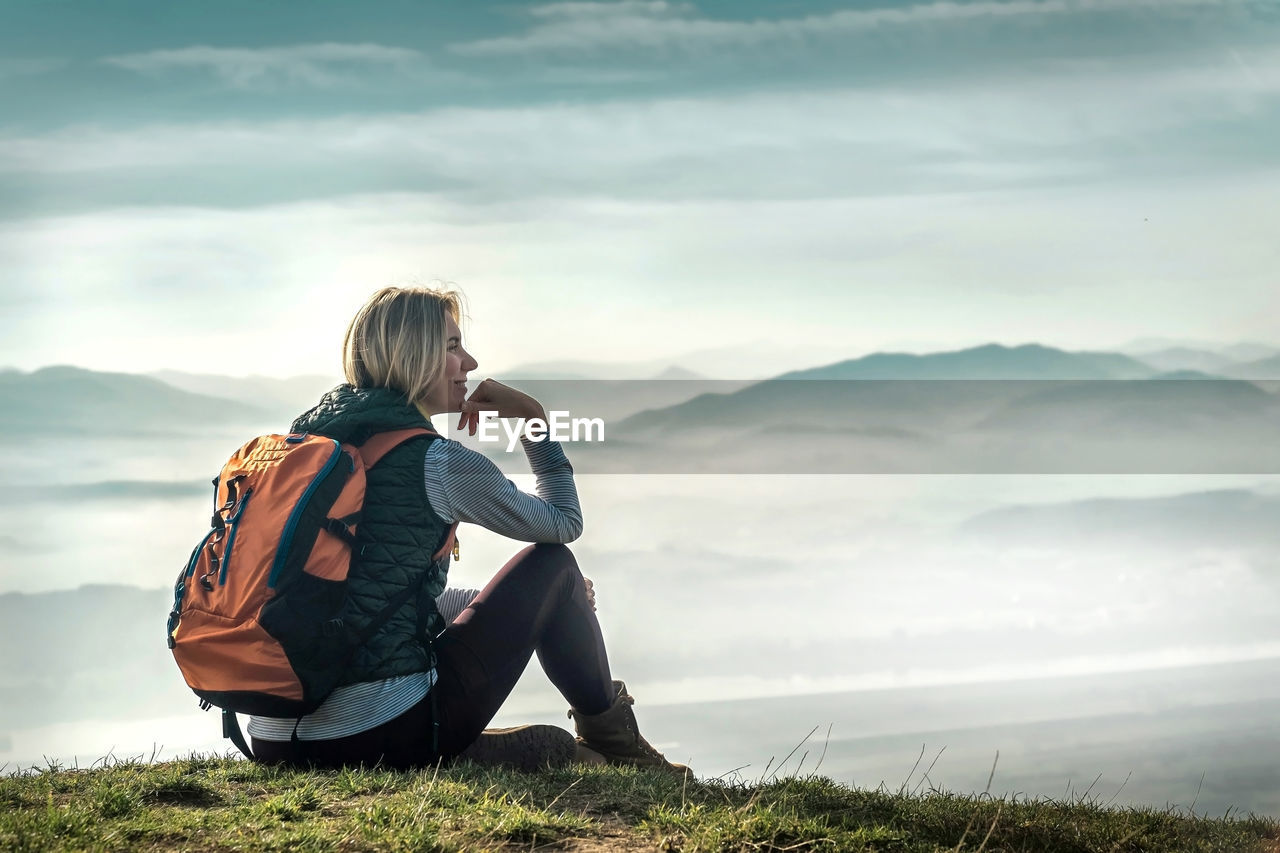 Happy woman tourist stay on green grass on peak of mountain and look on nice view. concept freedom.
