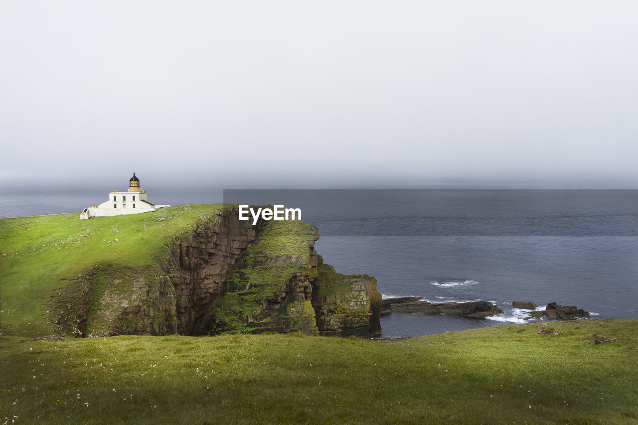 Scenic view of landscape with calm sea in background