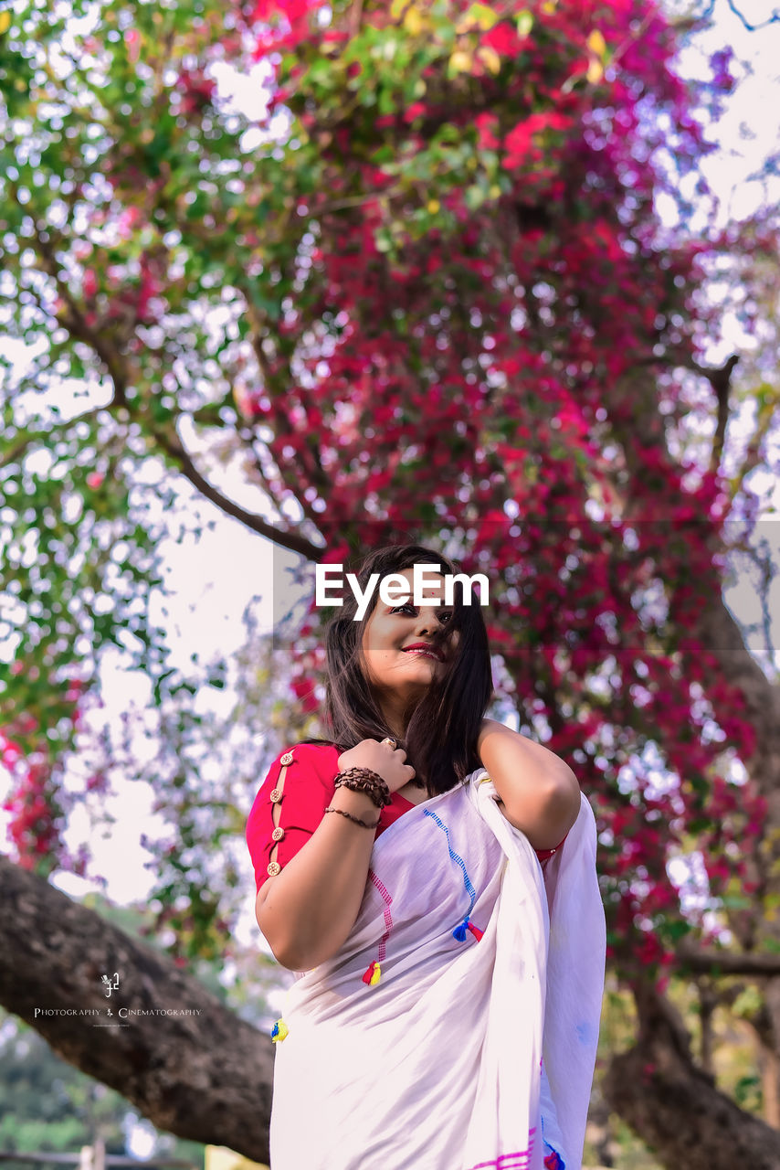 Low angle view of woman standing against pink trees