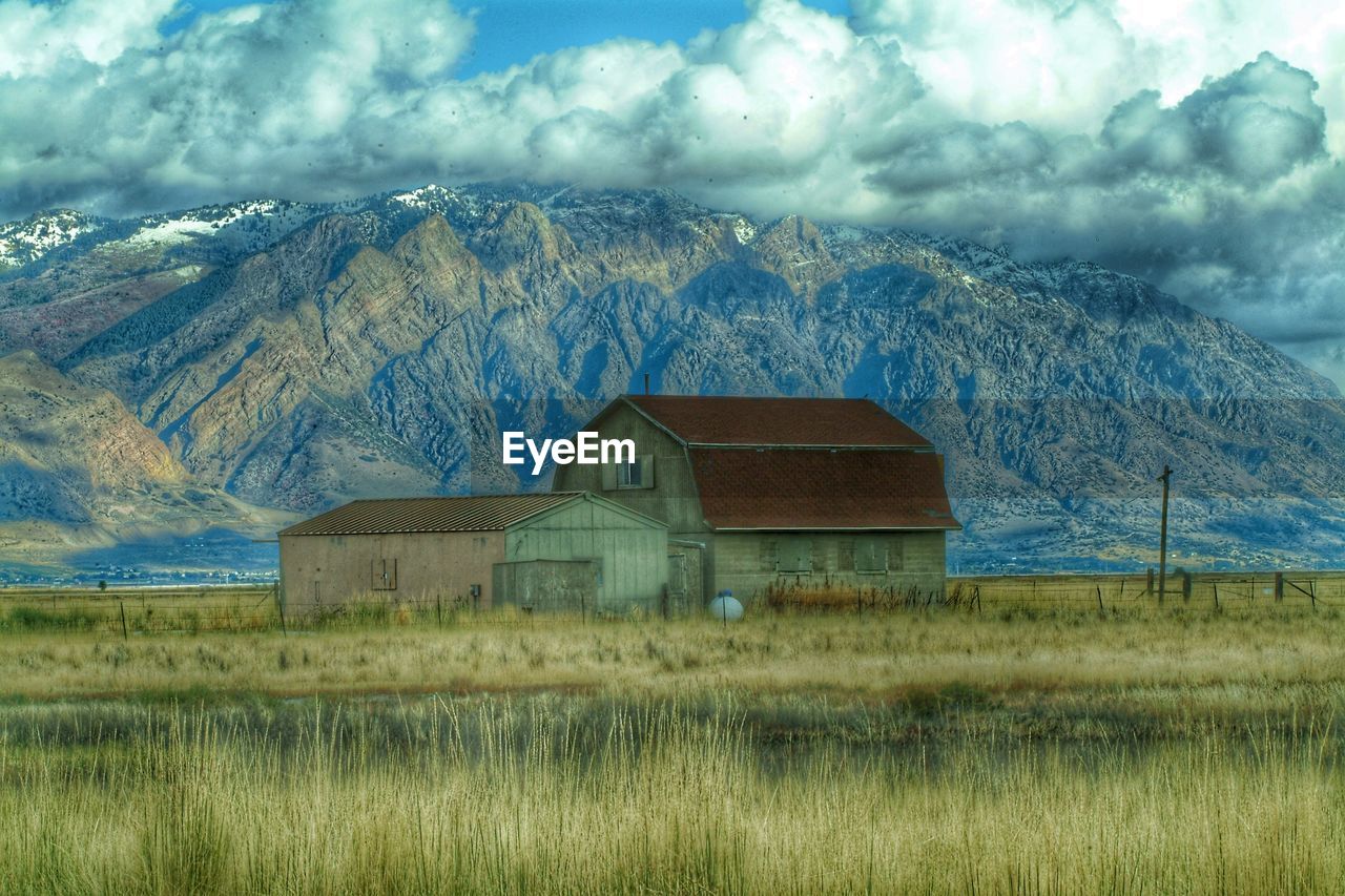 HOUSES ON FIELD AGAINST CLOUDY SKY