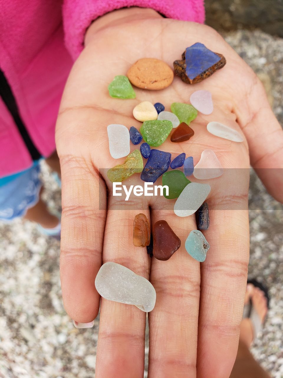 Cropped hand of woman holding multi colored stones