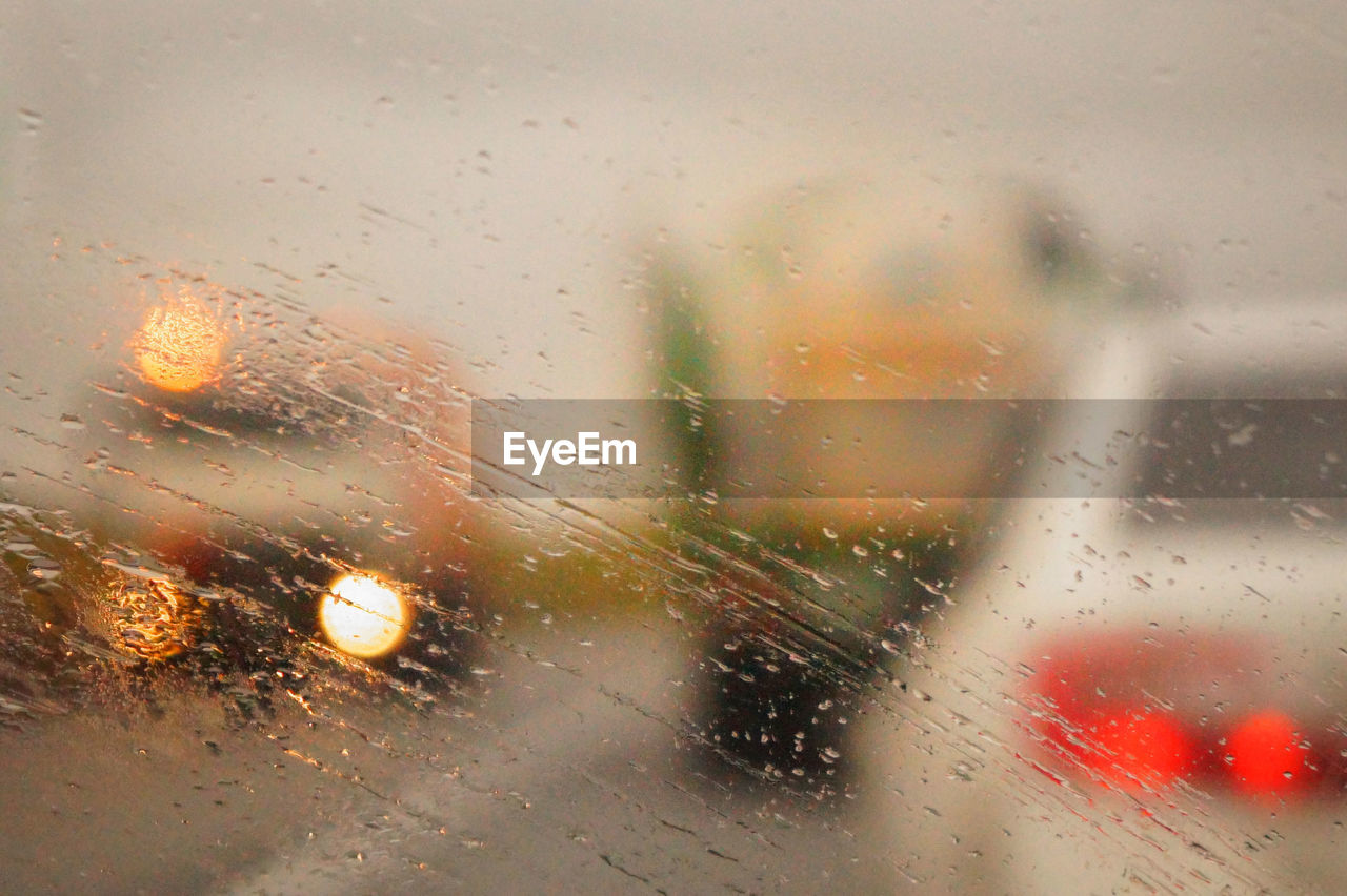 Cars on road seen through wet car windshield during rainy season