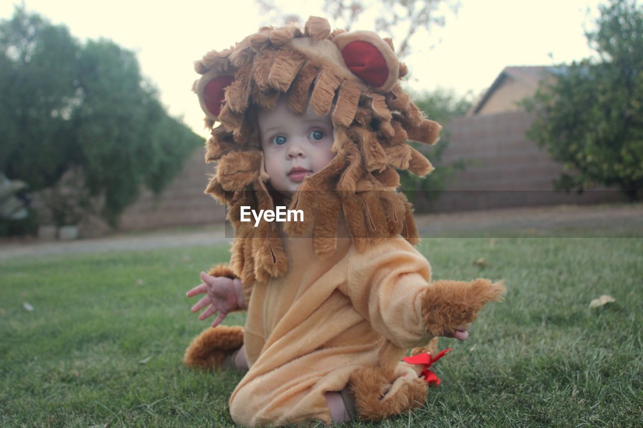 Portrait of cute baby girl wearing costume kneeling on land