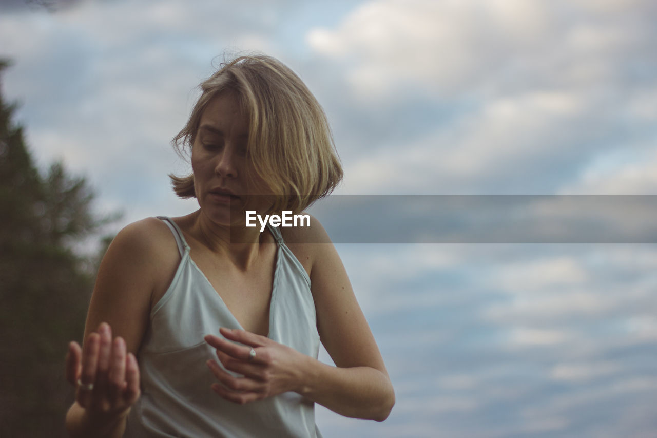 Beautiful woman dancing against cloudy sky