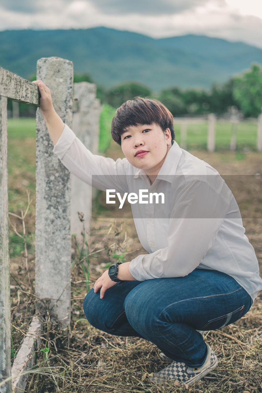 Portrait of young woman crouching at farm