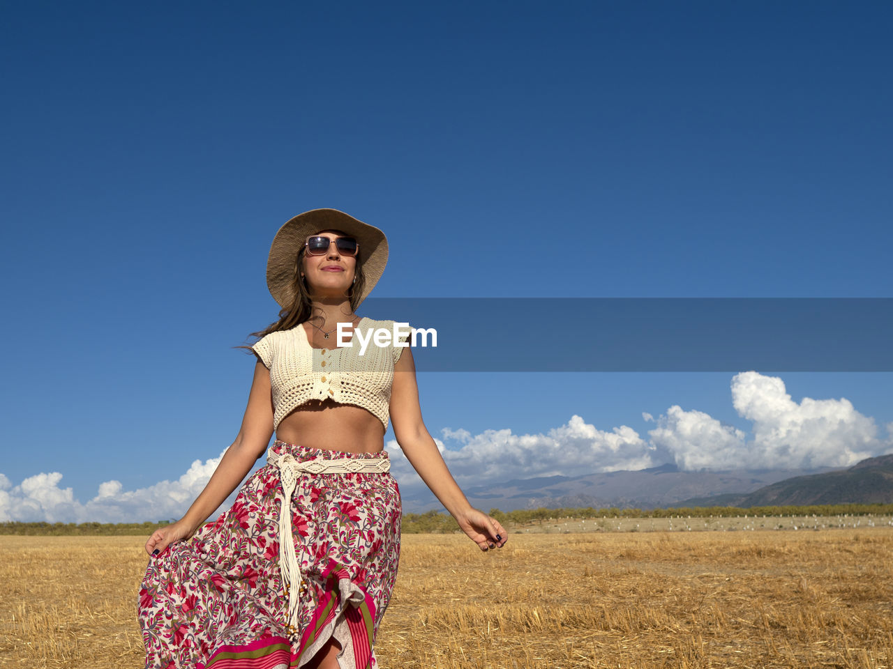 Portrait of woman standing on field against sky