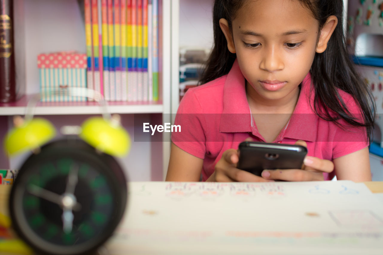 Little girl using mobile phone with wireless internet at home. education concept.