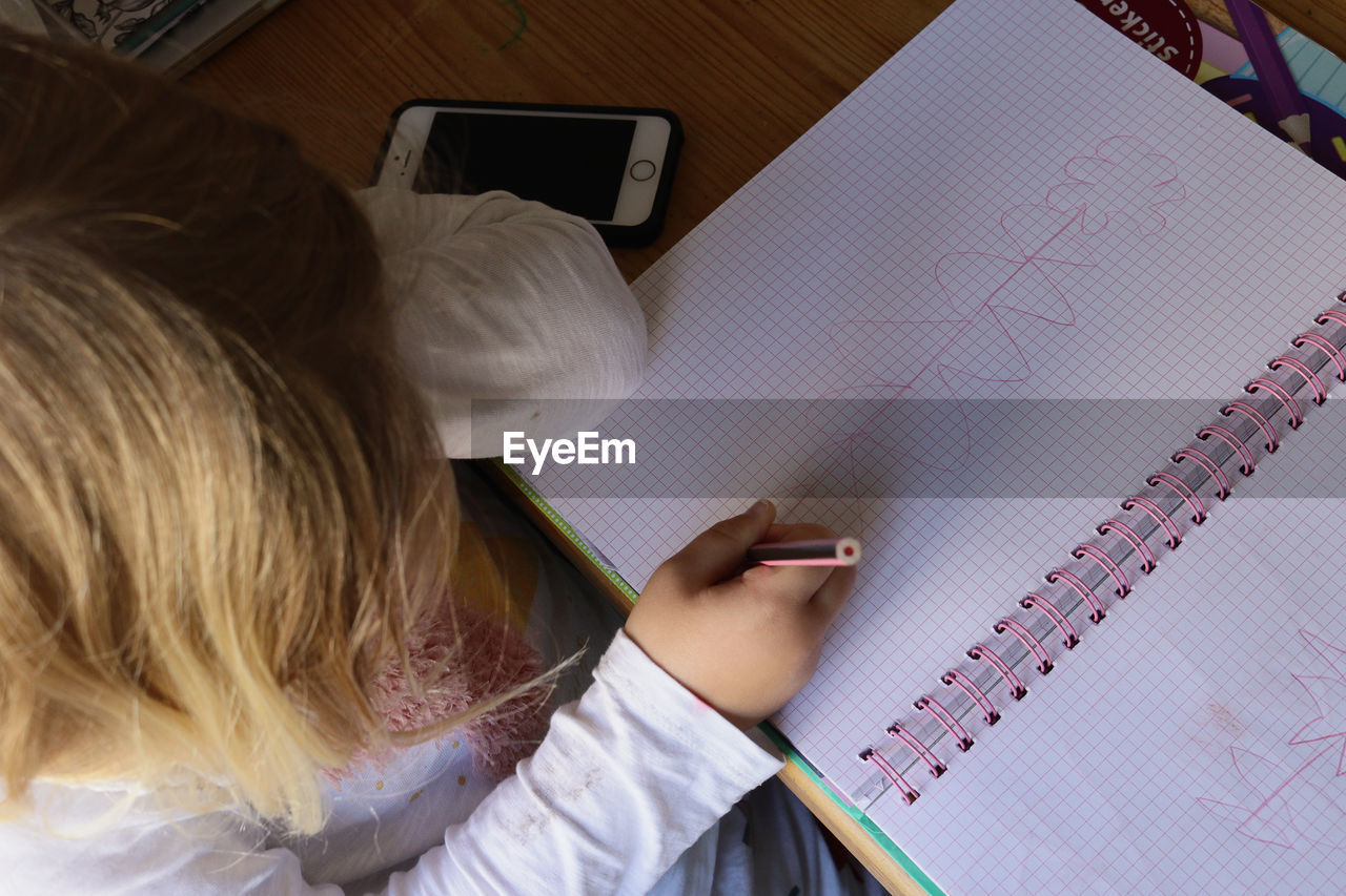 High angle view of girl drawing on book