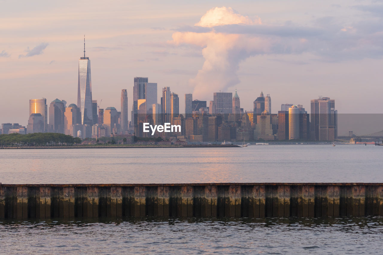 SEA AND BUILDINGS AGAINST SKY DURING SUNSET