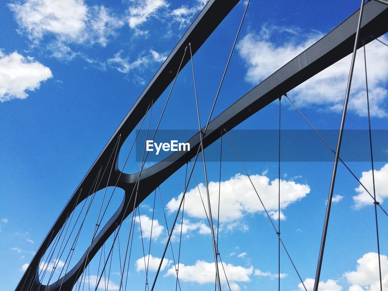 Low angle view of suspension bridge against cloudy sky