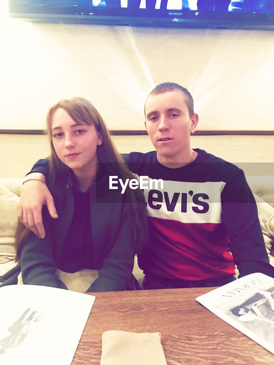 PORTRAIT OF A YOUNG COUPLE SITTING AT TABLE