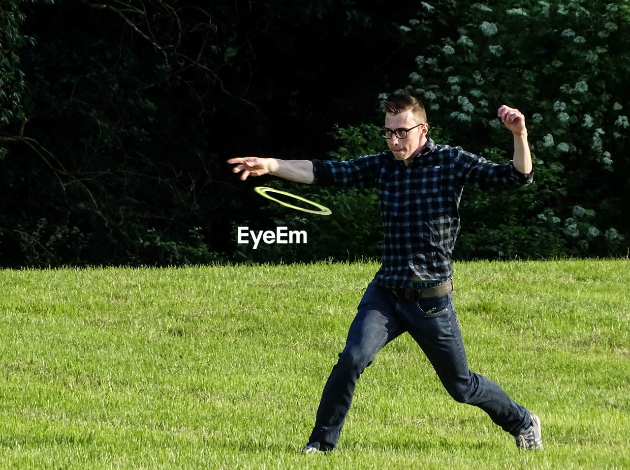 Full length of man walking while throwing plastic disc on grass