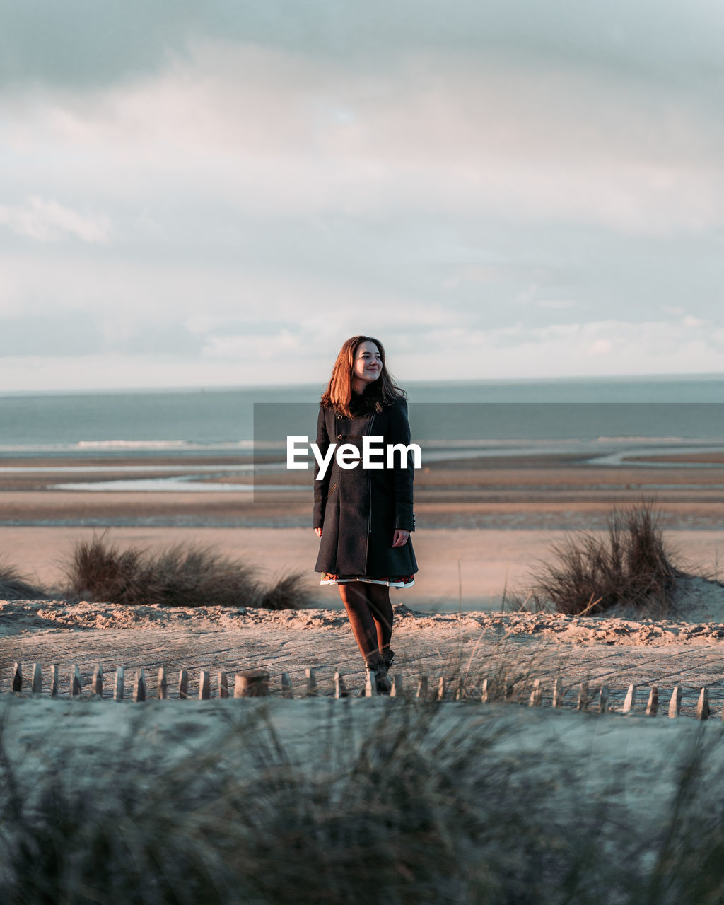 Full length of woman standing on beach against sky