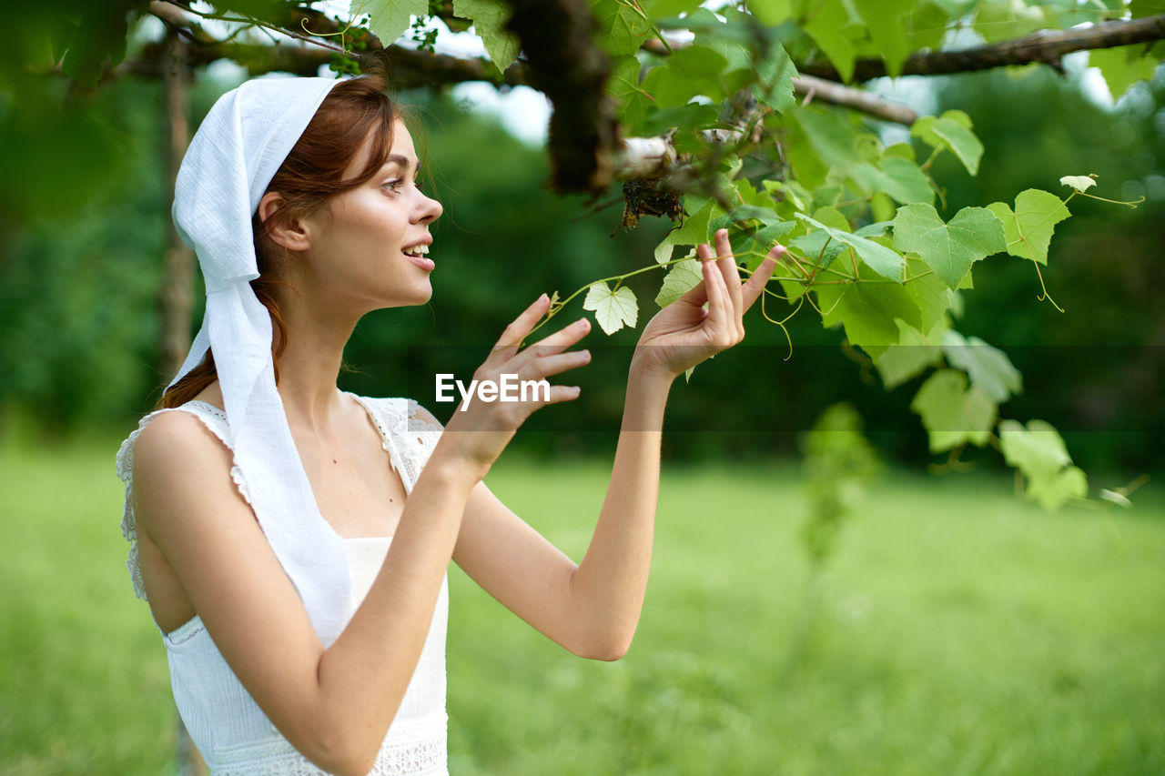 side view of young woman looking away while standing outdoors