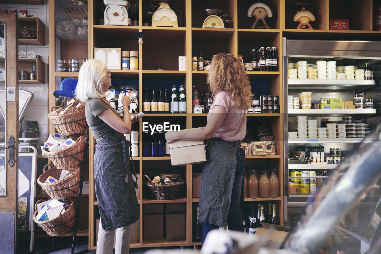 Female coworkers standing by rack in deli