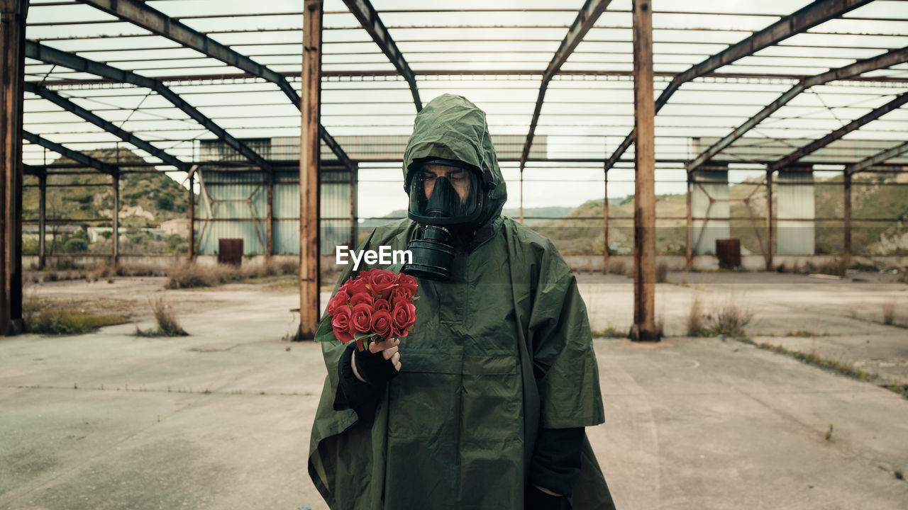 Soldier with bunch of red flowers and gas mask