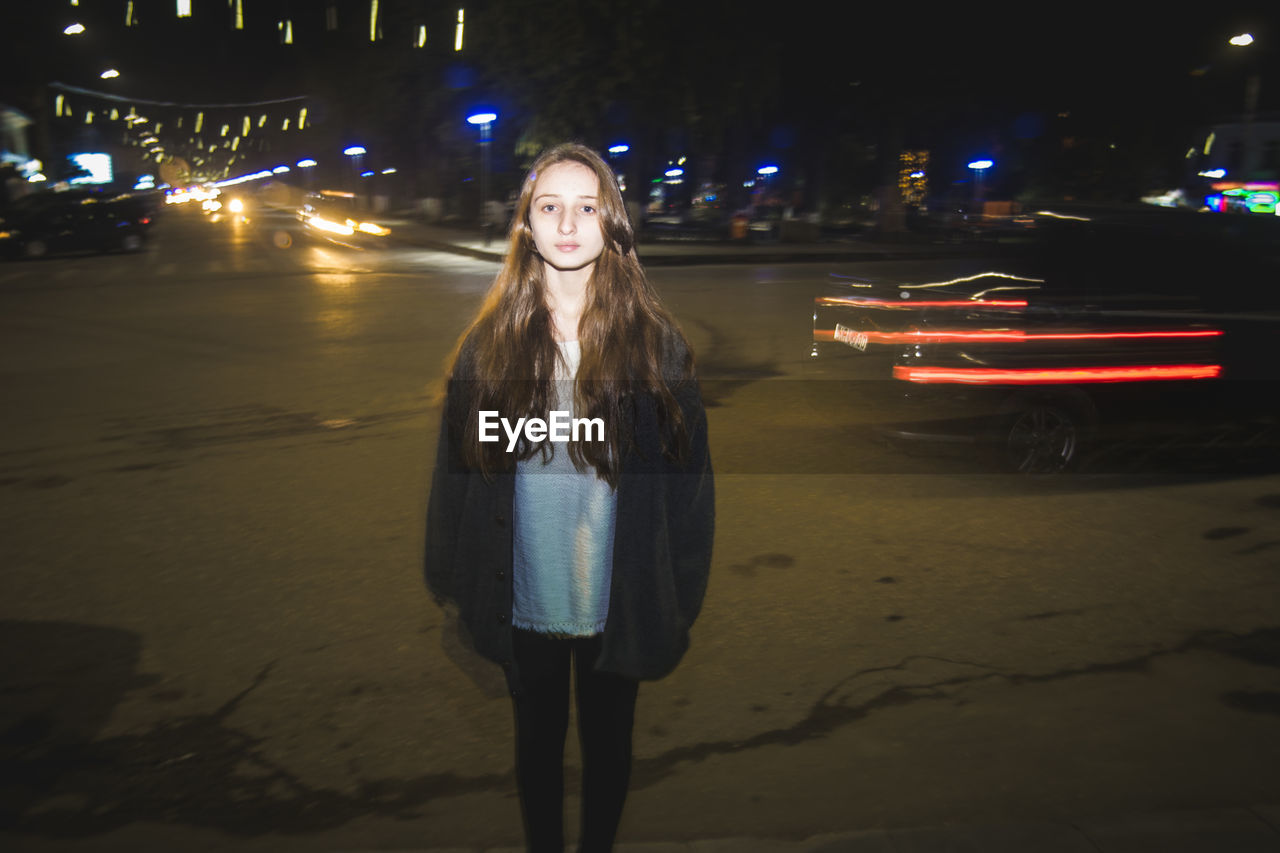Double exposure of light trails and teenage girl in city at night