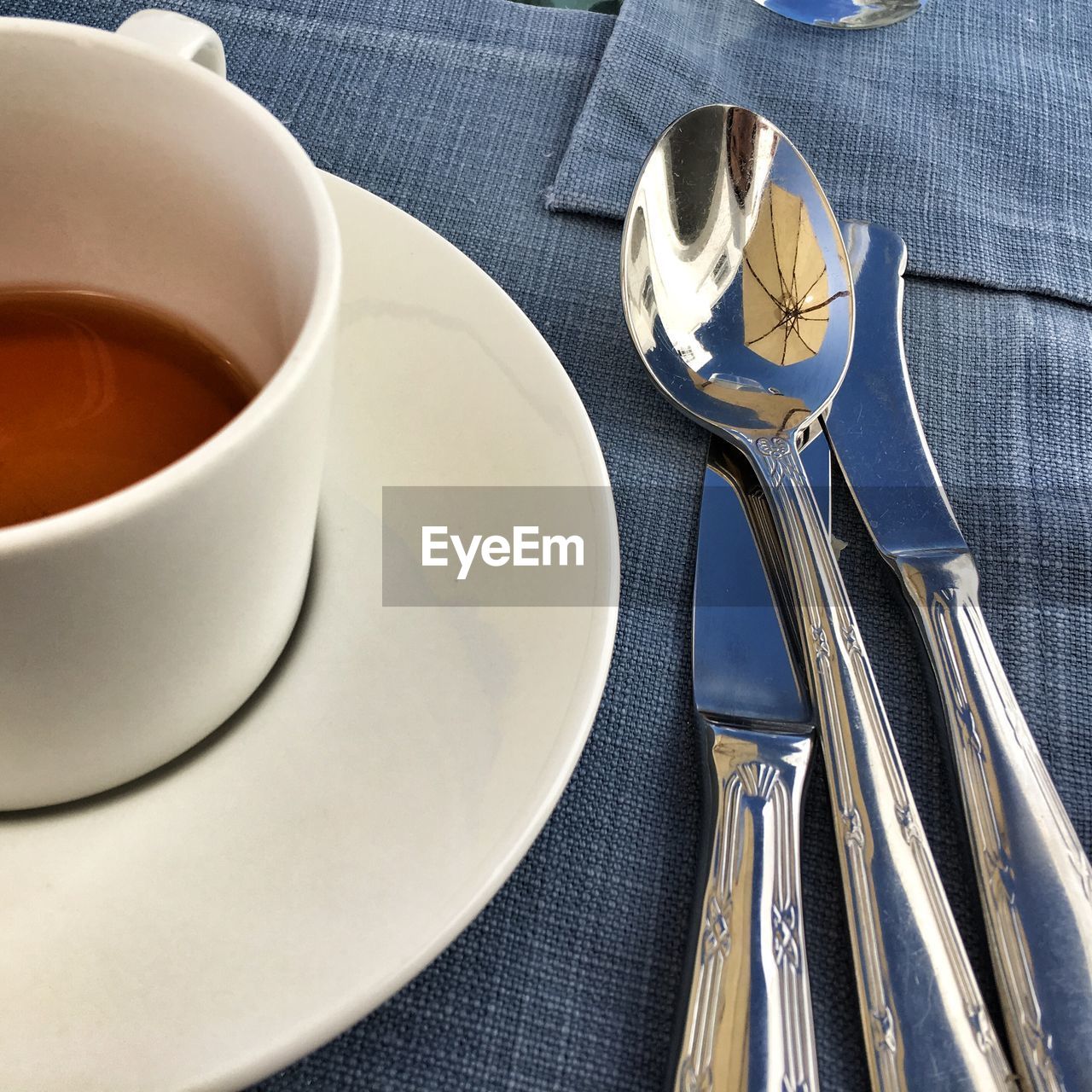 Close-up of tea cup with kitchen utensils on table