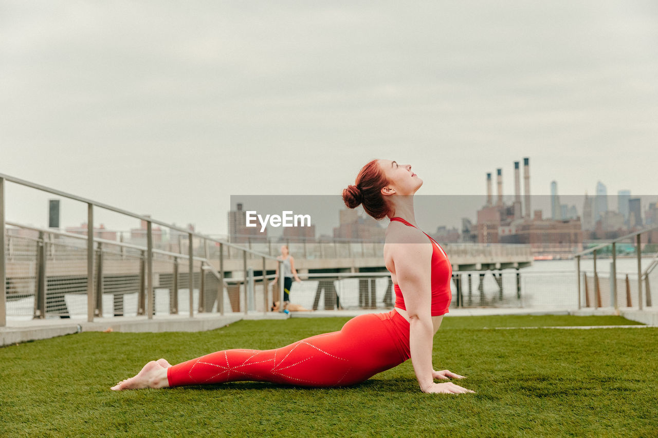Young female athlete stretching by waterfront in brooklyn.