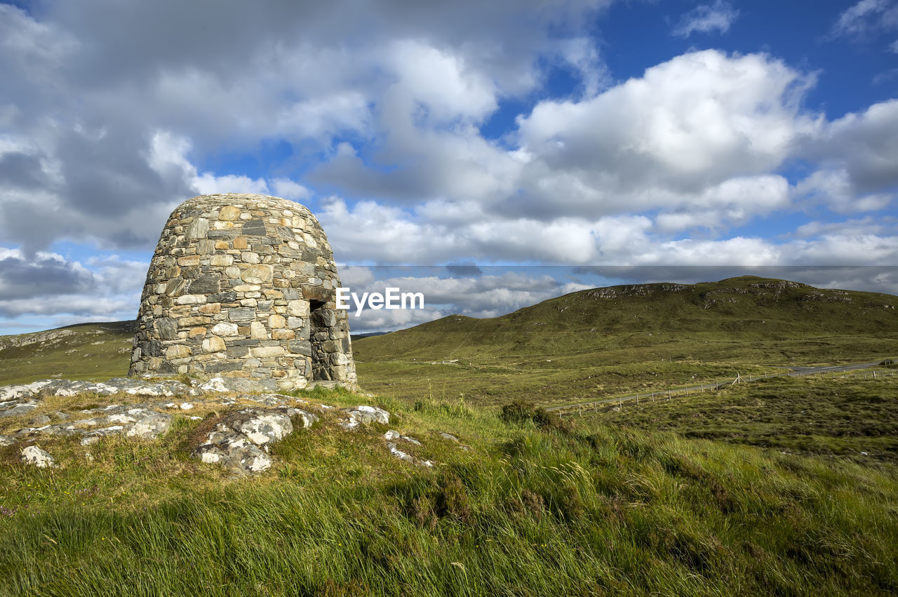 STONE STRUCTURE ON FIELD AGAINST SKY