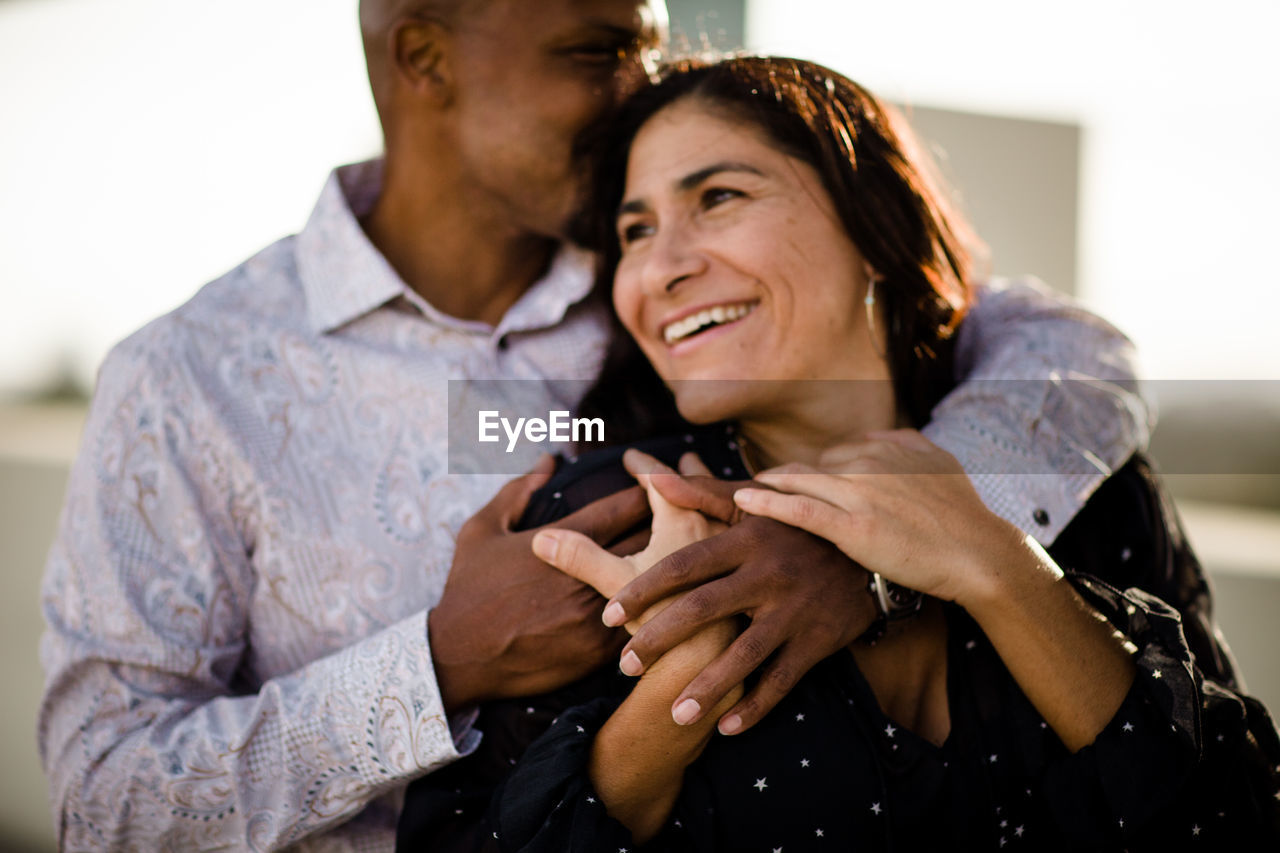 Multiracial late forties couple embracing at sunset in san diego