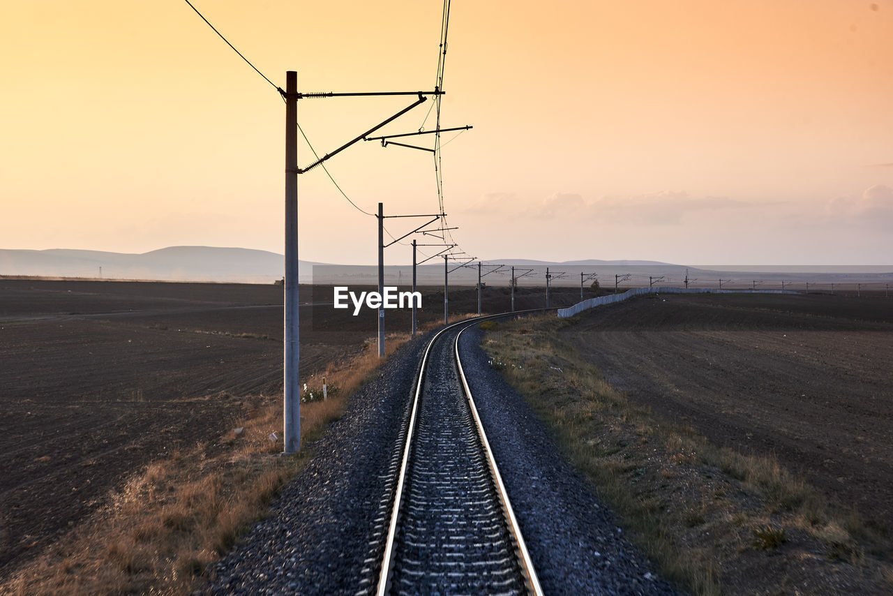Railroad track against clear sky during sunset
