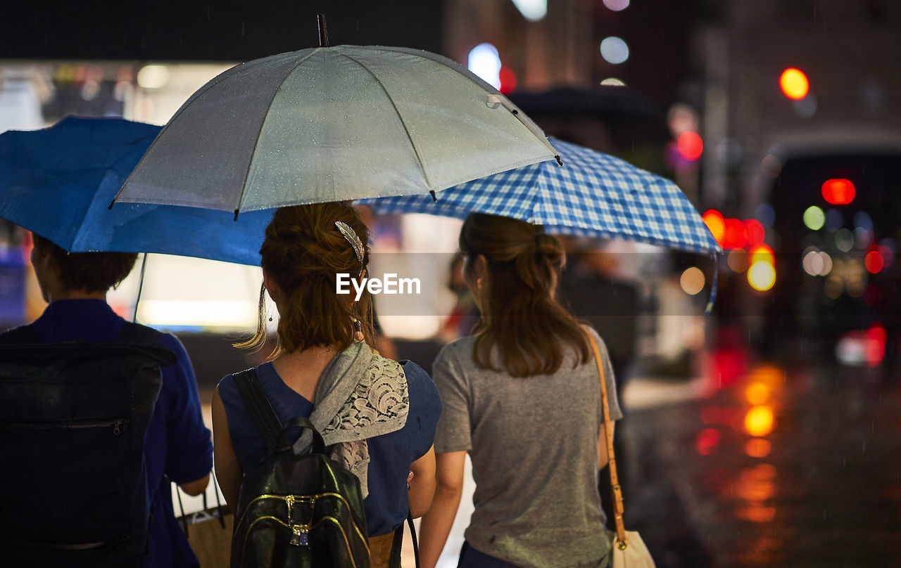 REAR VIEW OF WOMAN WITH UMBRELLA ON CITY STREET