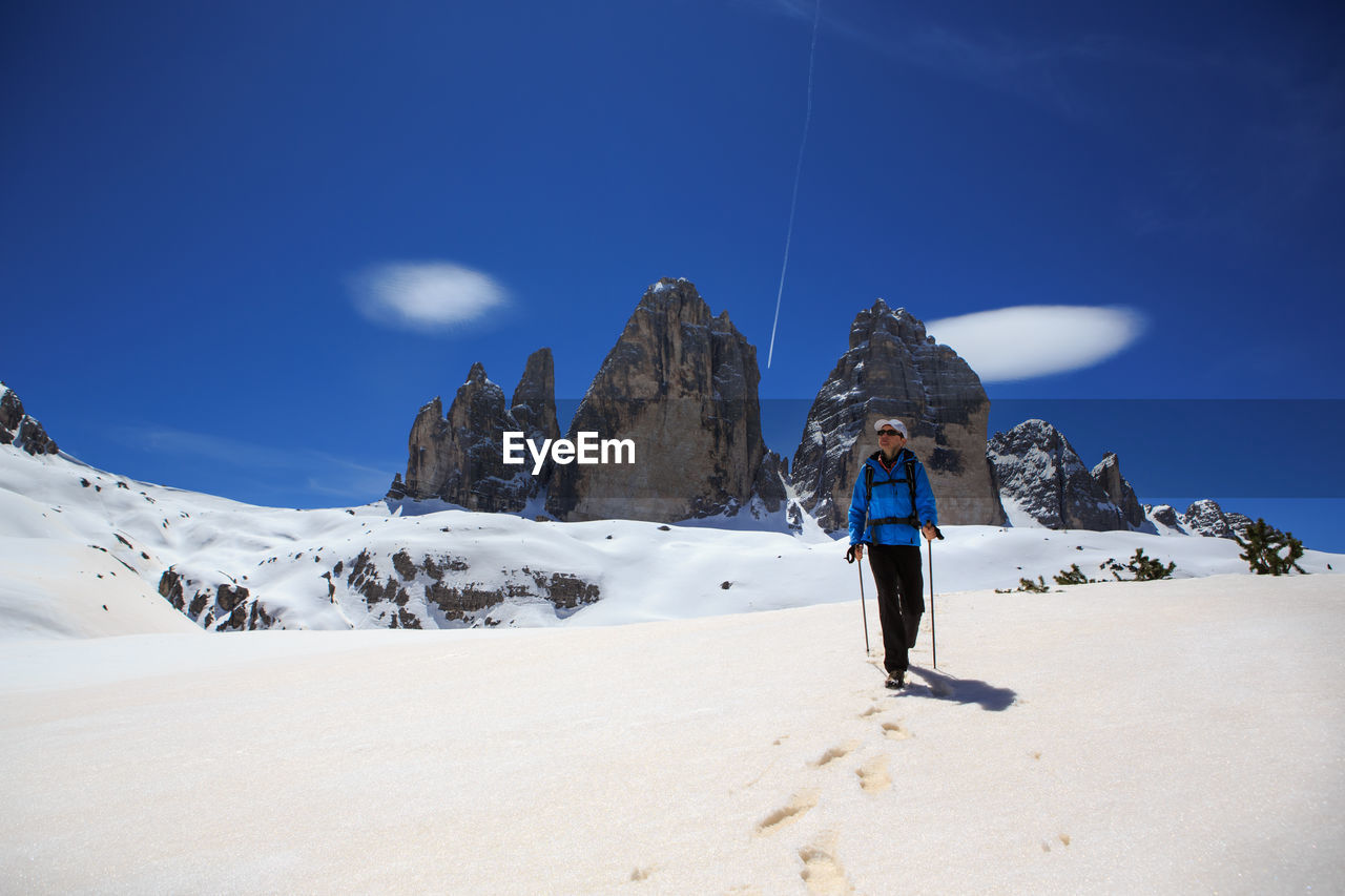 Mature man skiing on snowcapped mountain against sky