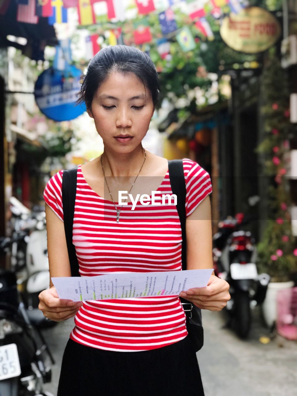 Woman holding paper while standing on city street