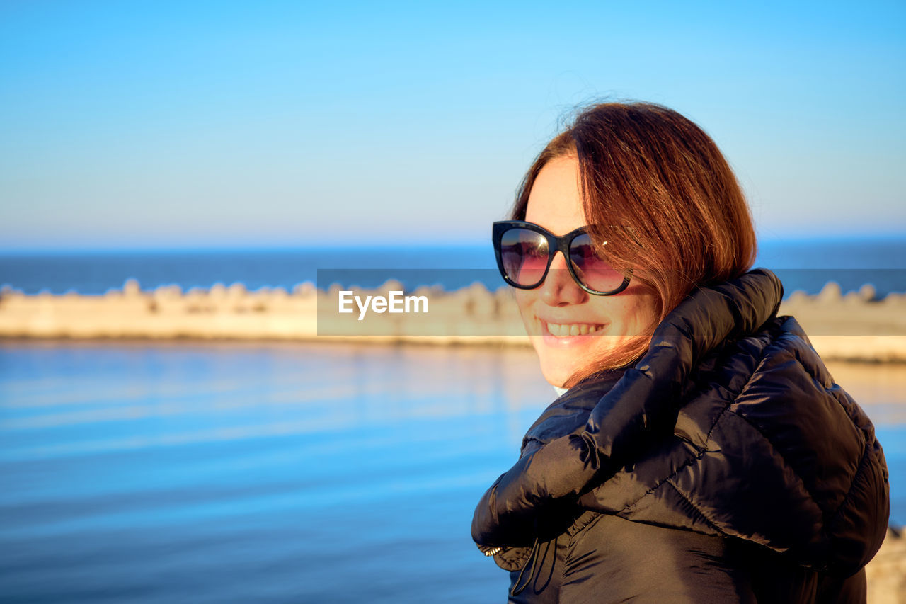 Young woman wearing sunglasses against sea