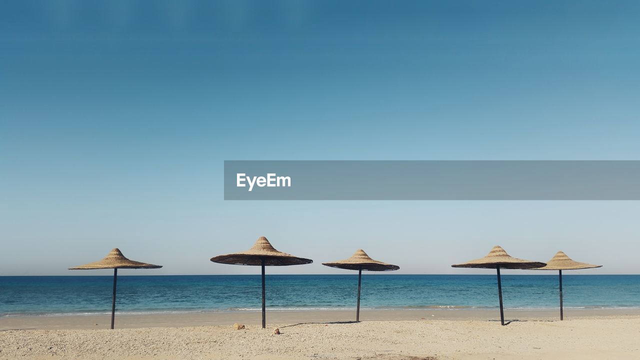 Sunshades at beach against clear sky