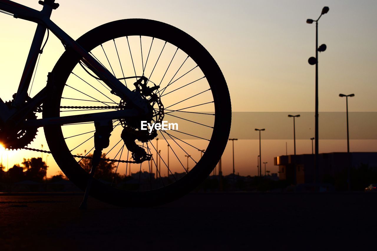 SILHOUETTE BICYCLE ON STREET AGAINST SKY DURING SUNSET