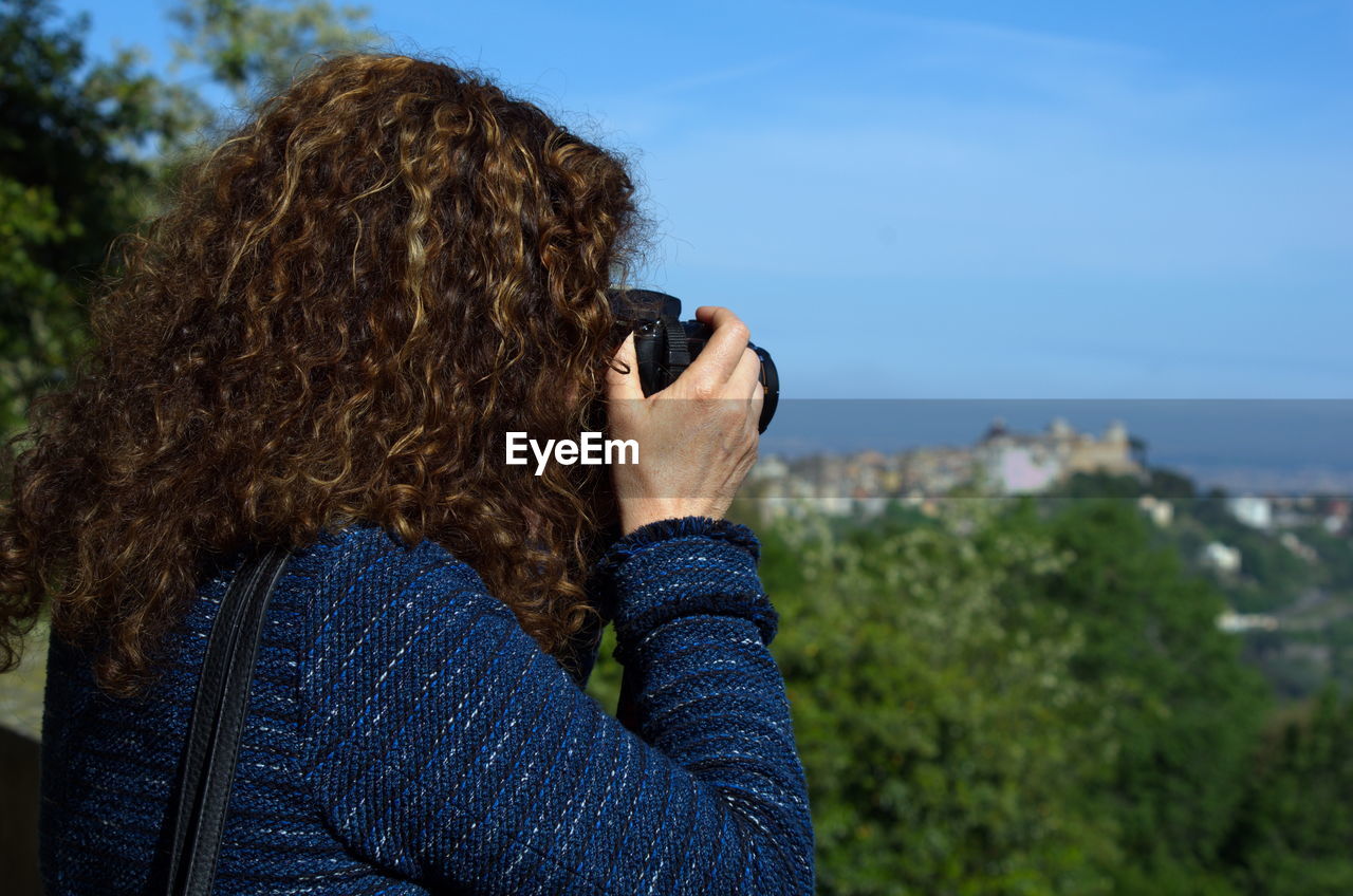 Portrait of woman using photo camera outdoors