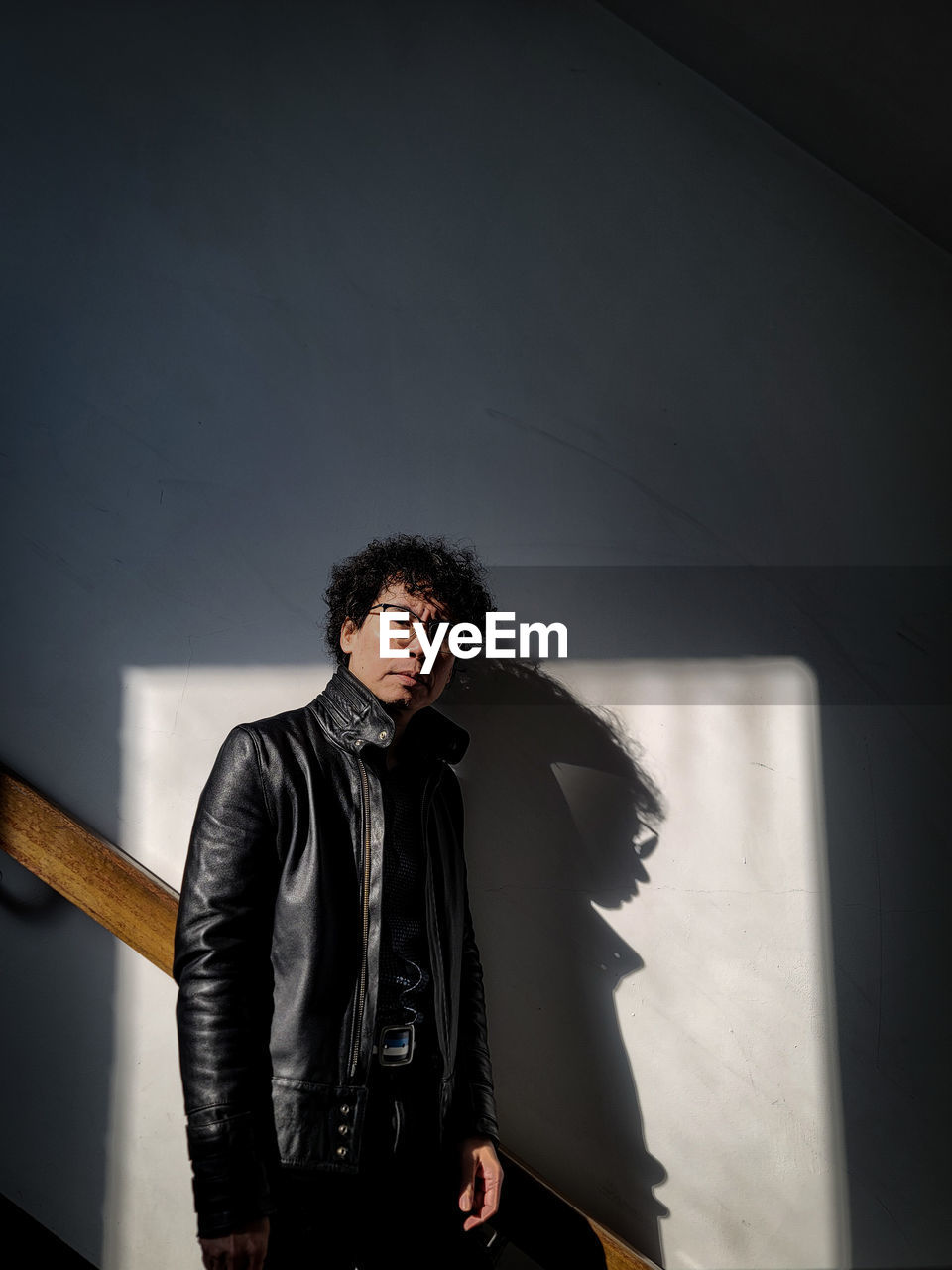 black, one person, fashion, adult, young adult, standing, men, indoors, portrait, front view, photo shoot, clothing, three quarter length, darkness, copy space, jacket, arts culture and entertainment, looking at camera, curly hair, leather jacket, waist up, hairstyle, shadow, architecture