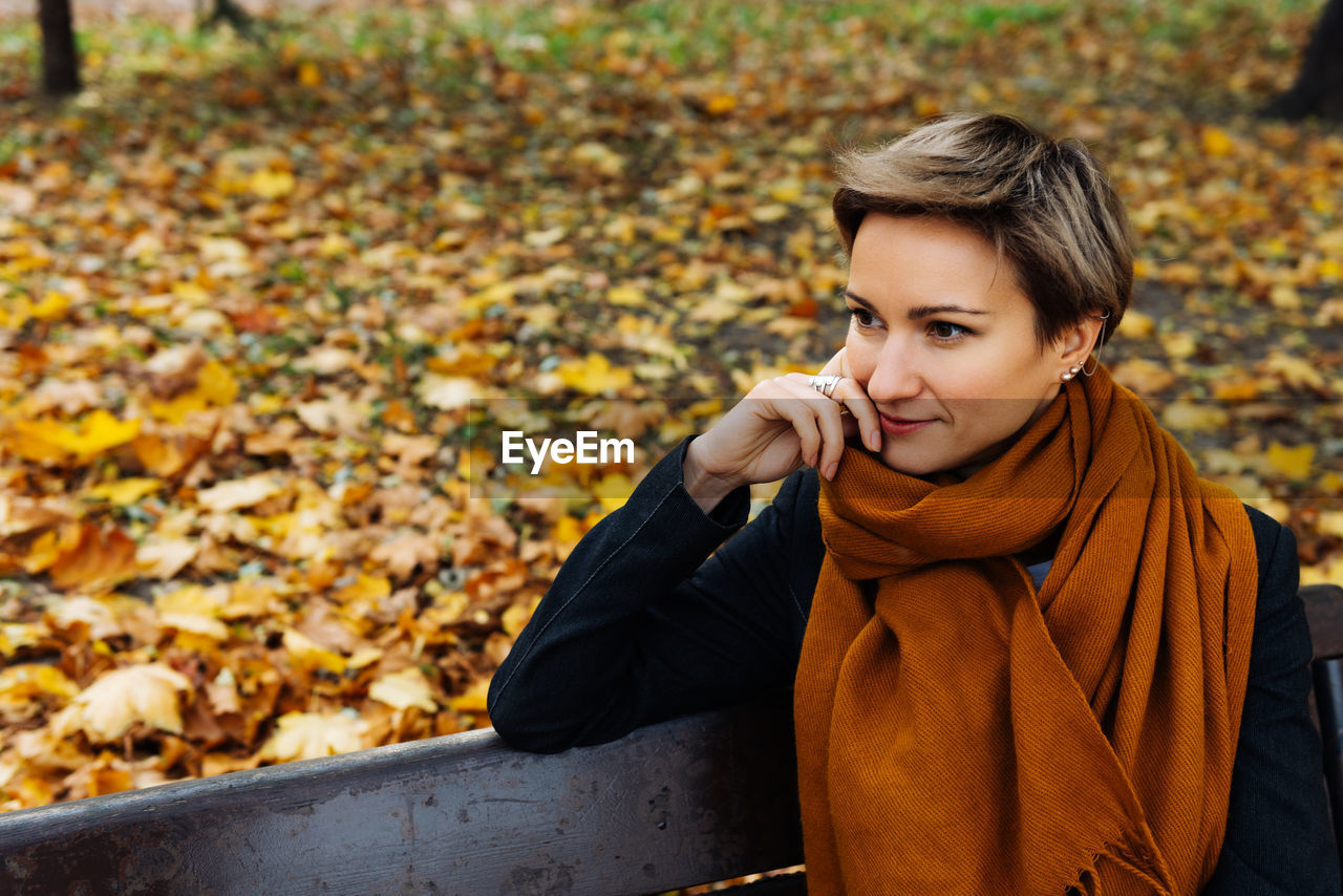Portrait of a short-haired blonde in a terracotta scarf in an autumn park