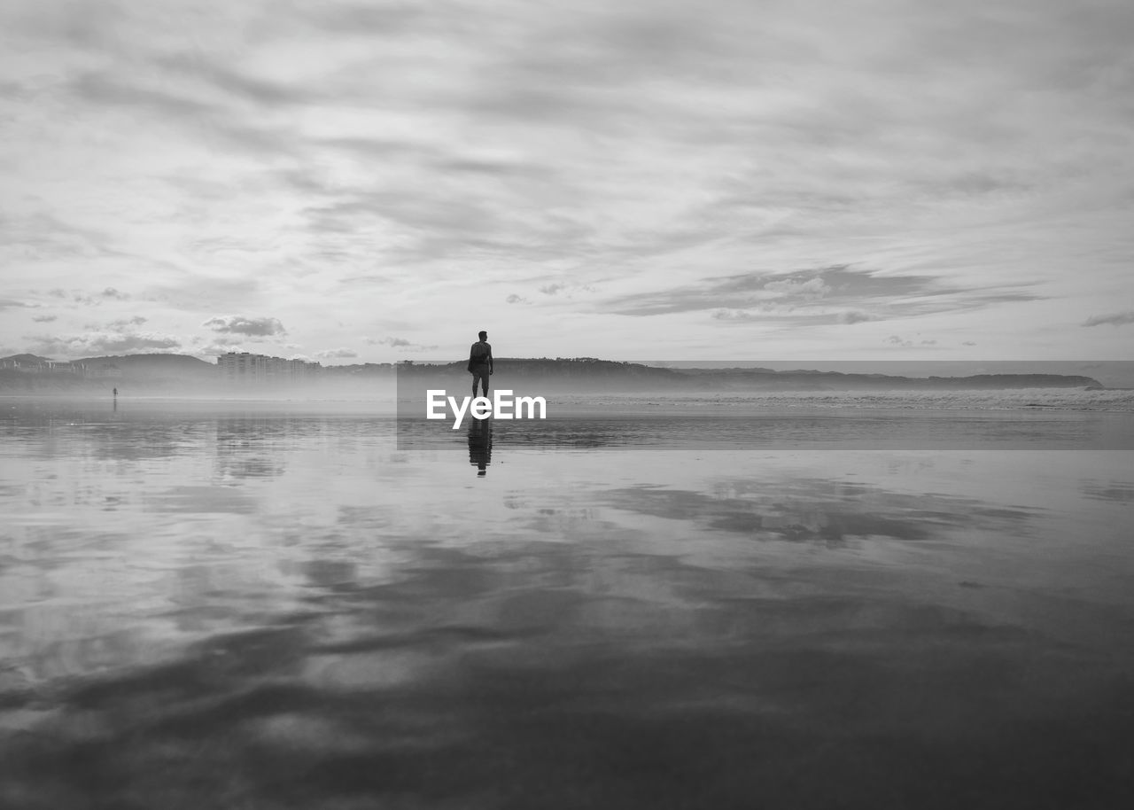 Silhouette man standing in sea against sky