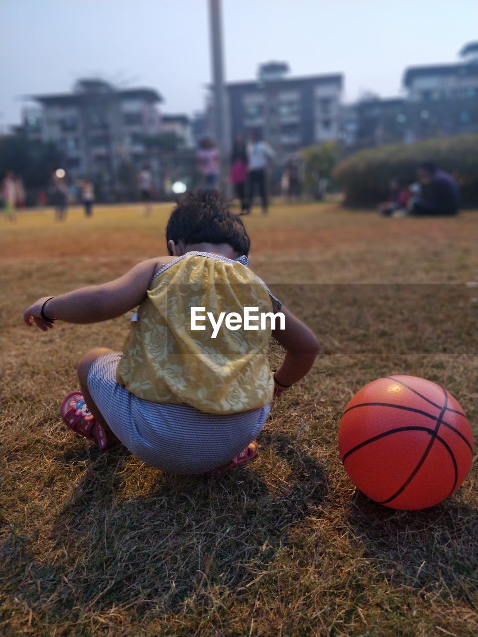 Rear view of baby girl crouching on field