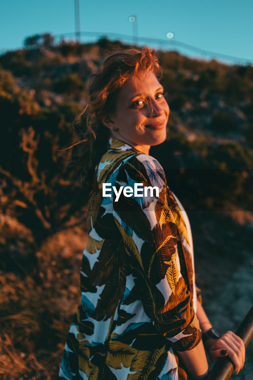 Portrait of young woman standing on rock