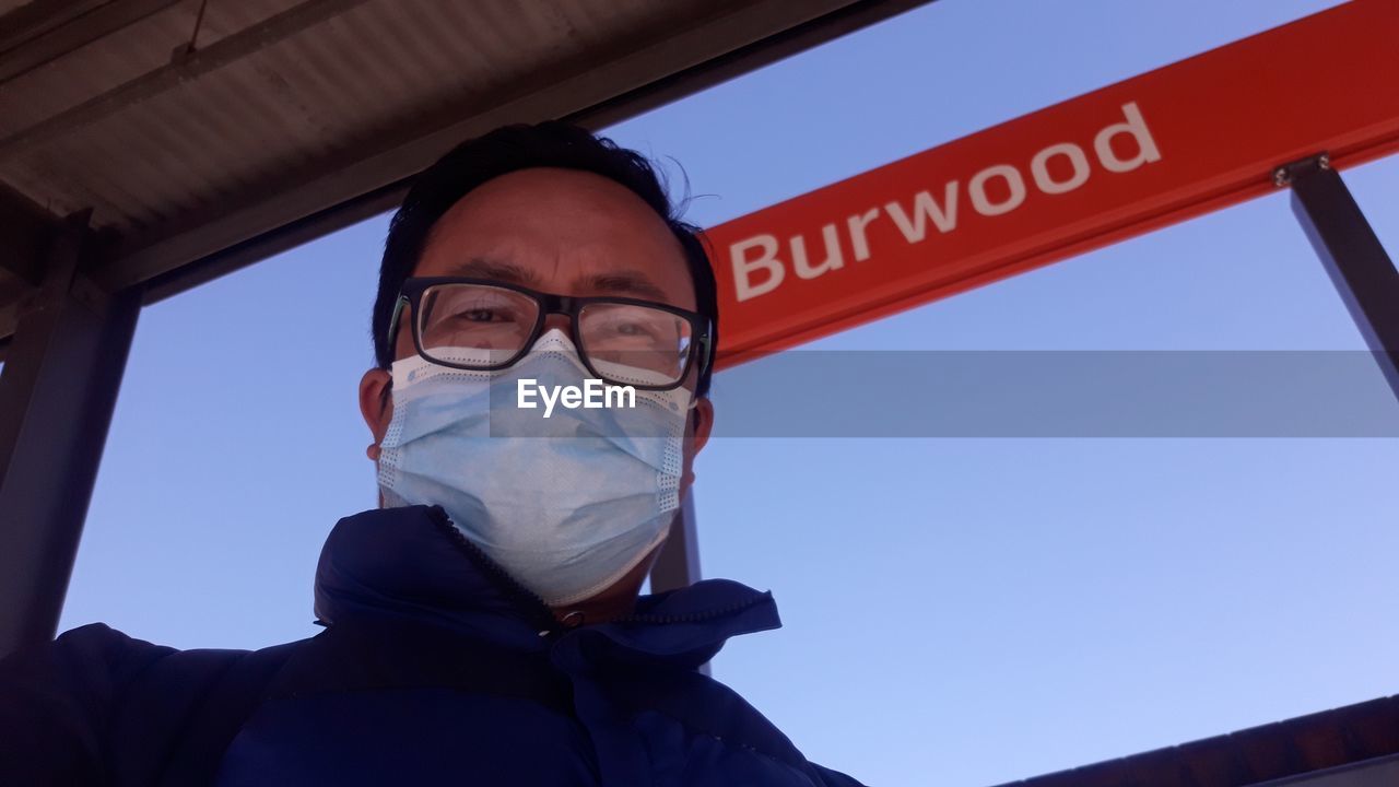 Low angle portrait of man wearing flu mask against sky