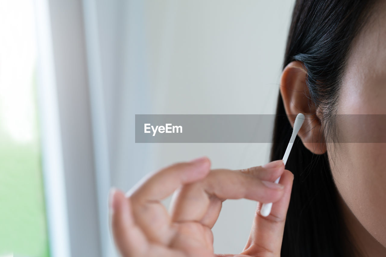 Woman cleaning ear with cotton swab. healthcare and ear cleaning