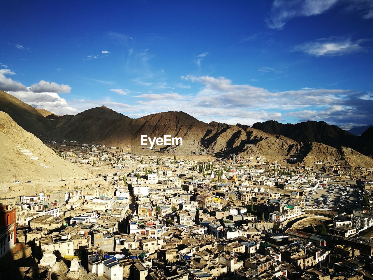 Aerial view of town by mountains against sky
