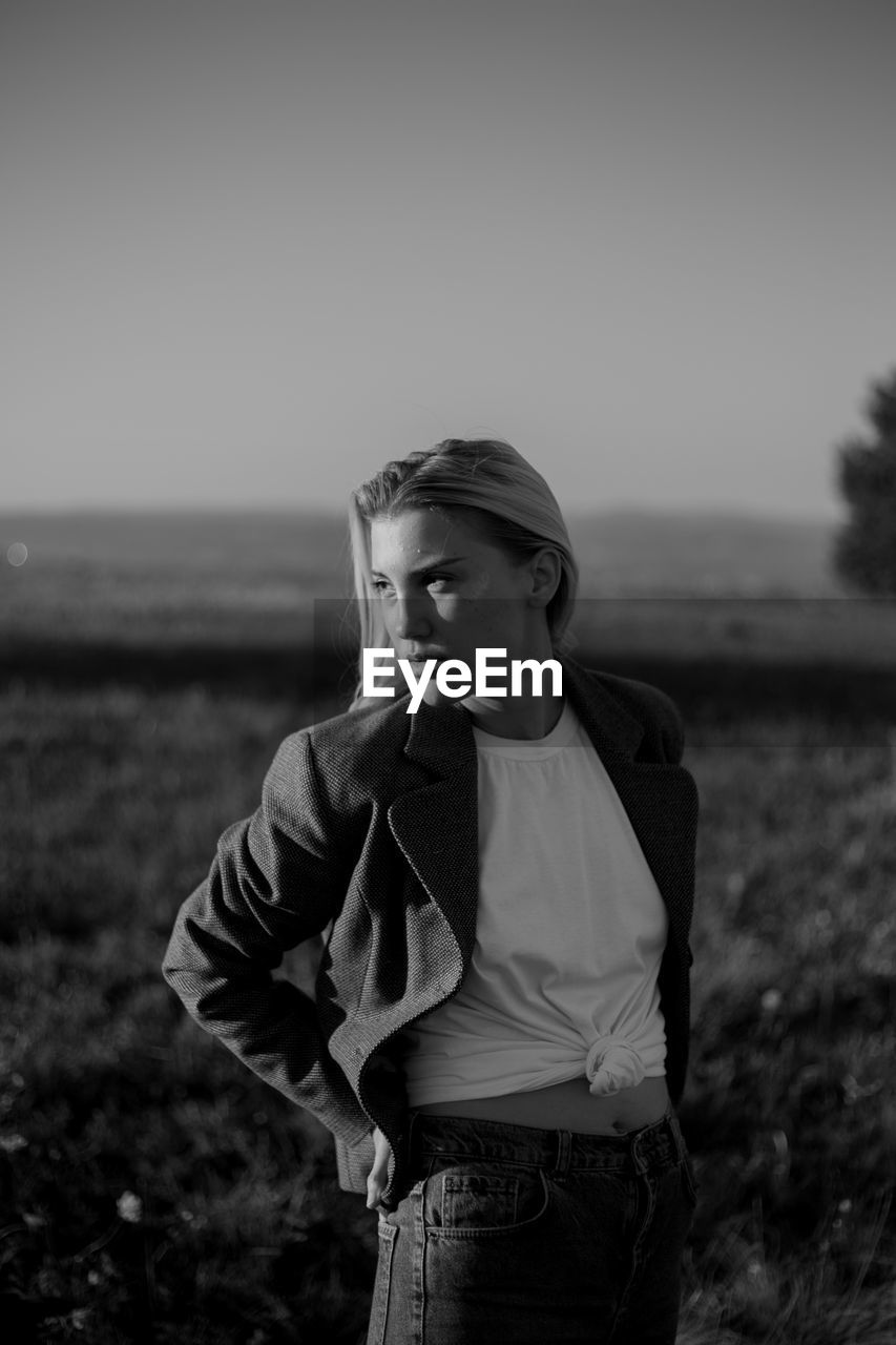 A young woman standing in a field during sunset