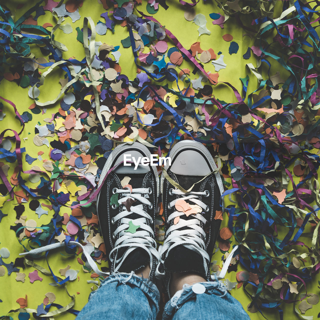 Feet seen from above on a floor full of colorful confetti