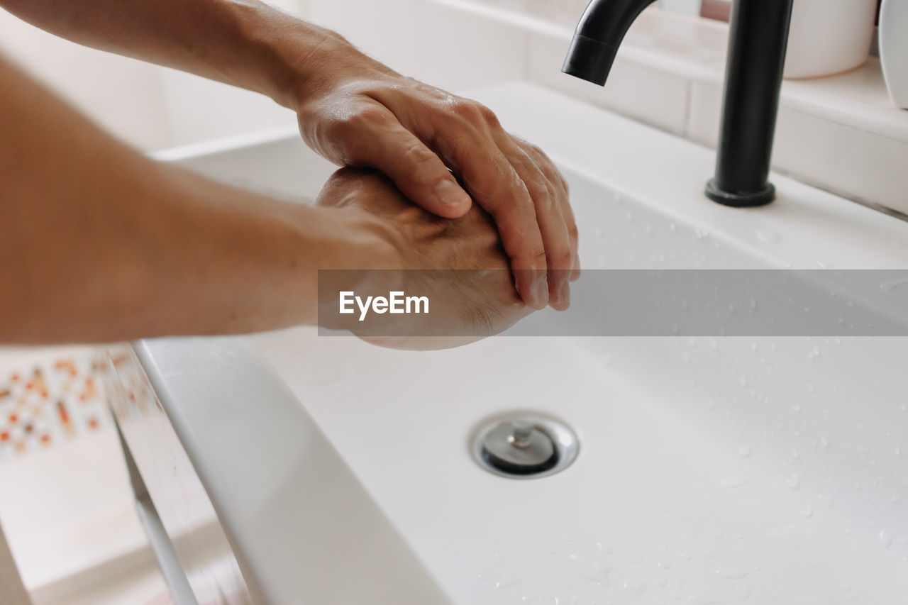 HIGH ANGLE VIEW OF HANDS IN BATHROOM AT HOME