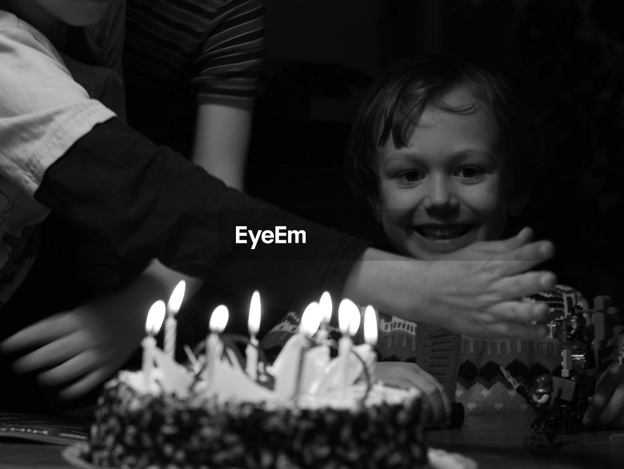 Portrait of smiling boy by birthday cake in darkroom